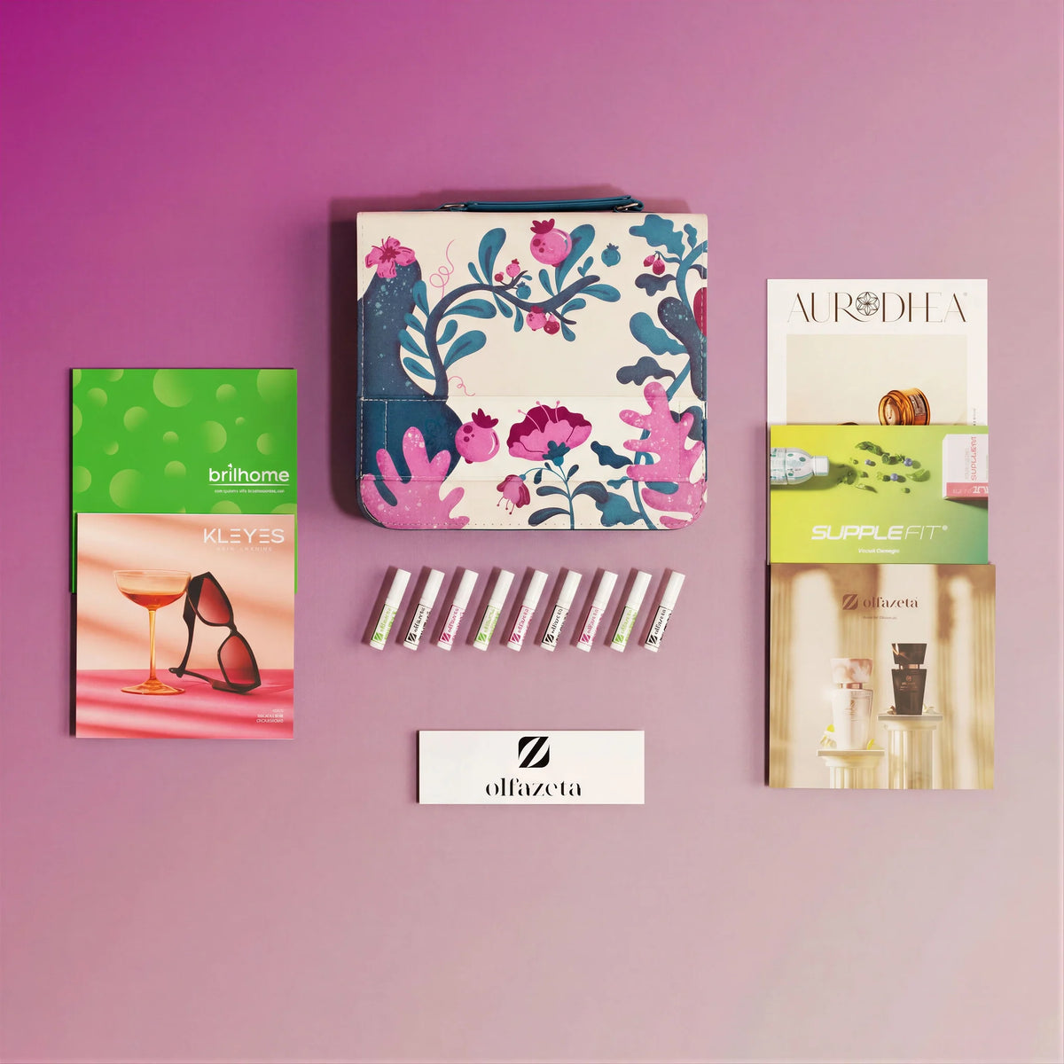 Kit d'échantillons Olfazeta by Chogan : fioles, trousse à motif floral et catalogues de marques sur fond rose mauve