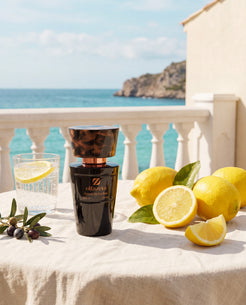 Flacon noir Olfazeta by Chogan Millésime N°33 sur un balcon en bord de mer, citrons frais et olives