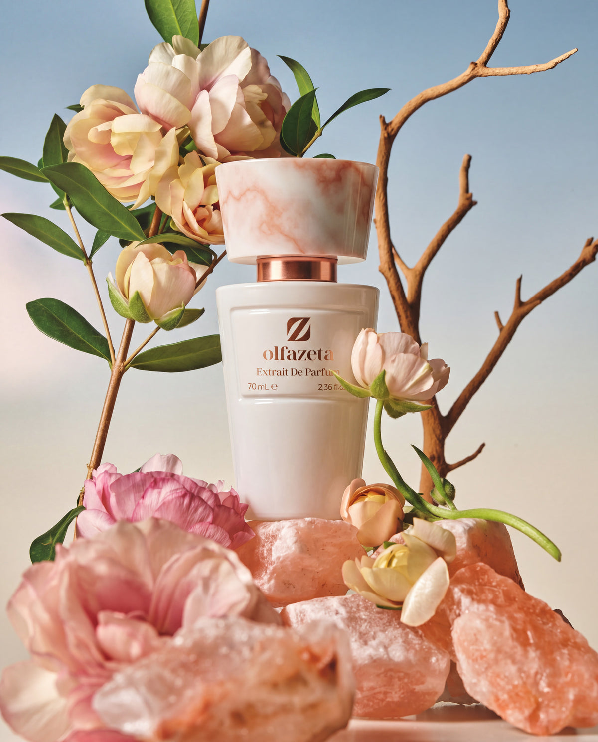 Flacon blanc Olfazeta by Chogan Millésime N°10 sur roches de sel rose parmi roses pâles et branches nues