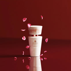 Flacon blanc Olfazeta by Chogan Millésime N°161 sous une pluie de pétales de rose roses sur fond bordeaux